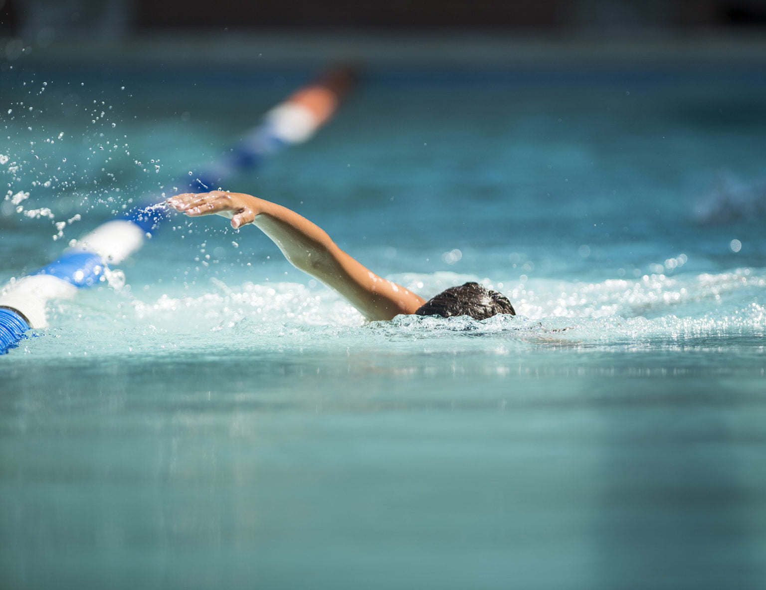 Athlete swimming in a pool getting closer to the finish line in a competition