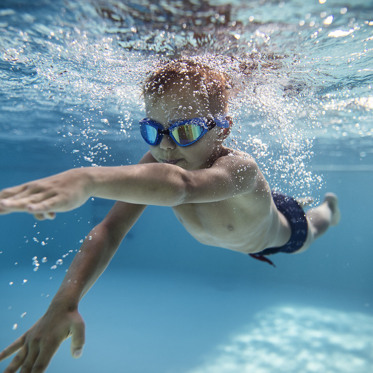 Portrait of little boy swimming underwater in the pool. Sunny summer day.
Nikon D850