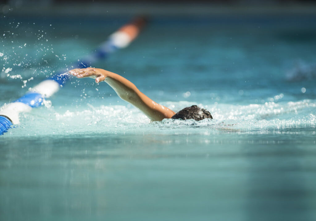 Athlete swimming in a pool getting closer to the finish line in a competition